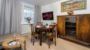 Et spiseområde med et træbord, stole og et buffetskab. En tv-skærm viser ordet "NETFLIX".