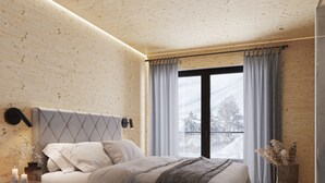 A modern bedroom with a wooden ceiling, a large bed with a headboard, a bedside table with candles, and a view of the outdoors through a window. - Apartment in Saalbach Near ski Area (Saalbach-Hinterglemm)