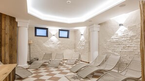 A spa area with checkered flooring, lounge chairs, and a stone wall. - Apartment in Saalbach Near ski Area (Saalbach-Hinterglemm)