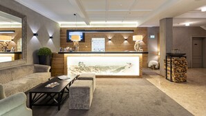 A lobby with a reception desk, seating area, and a large mirror. - Exclusive Suite in the ski Area (Saalbach-Hinterglemm)