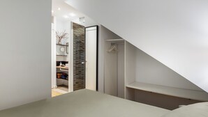 A modern bedroom with a sloped ceiling, a walk-in closet, and a visible bathroom. - Cozy and quiet apartment (Barcelona)