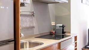 A modern kitchen with stainless steel appliances, wooden cabinets, and a built-in oven. - Cozy and quiet apartment (Barcelona)