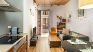 A compact living space with a kitchenette, a dining area, and a seating area with a sofa and armchair. - Cozy and quiet apartment (Barcelona)