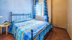 Een slaapkamer met een bed, nachtkastje en raam met gordijnen.