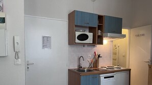 A compact kitchen with a microwave, stove, and dishwasher, wooden cabinets, and a white door.
