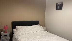 A single bed with a dark headboard, white bedding, and a small bedside table with a red lamp. - Renovated apartment with terrace and parking in Cauterets (Cauterets)