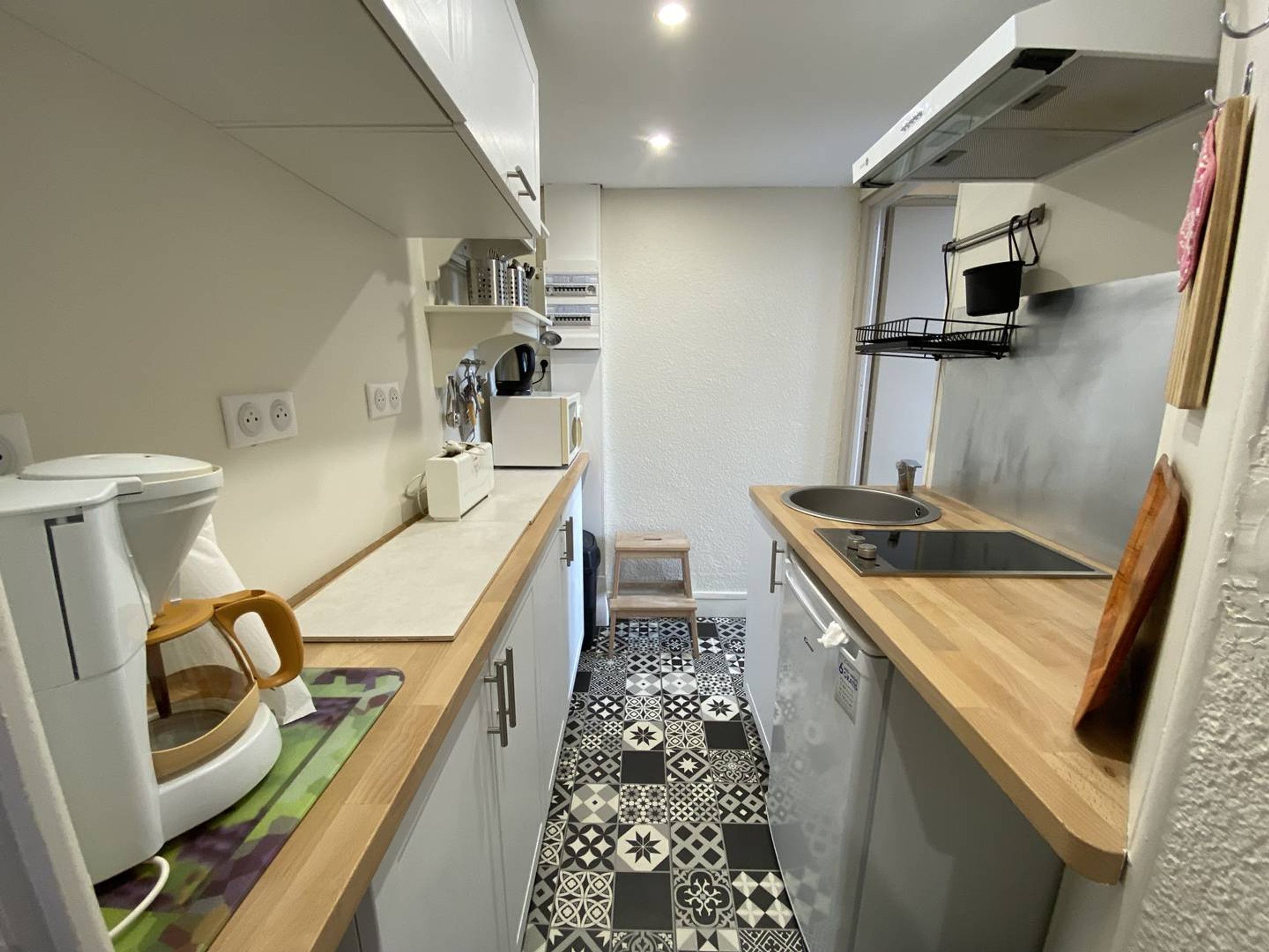 A compact kitchen with a sink, a coffee machine, and a microwave.