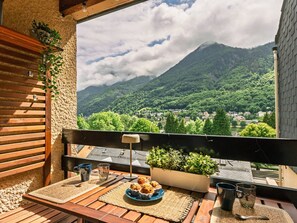 A balcony with a view of a mountain, a table with a plate of muffins, and a potted plant. - New apartment for 6, balcony, parking in Cauterets (Cauterets)
