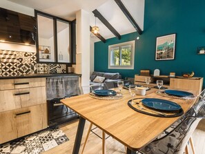 A modern kitchen with a wooden table set for dining, a sofa, and a window with a view. - New apartment for 6, balcony, parking in Cauterets (Cauterets)