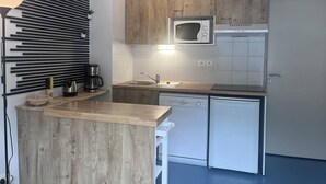 Une cuisine compacte avec des meubles en bois, un four à micro-ondes, un évier et un lave-vaisselle.