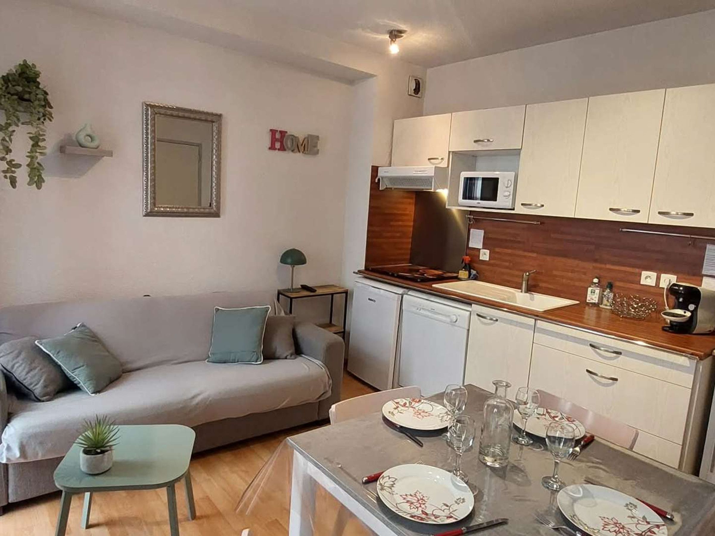 Un espace de vie compact comprenant une kitchenette, un coin repas et un canapé.