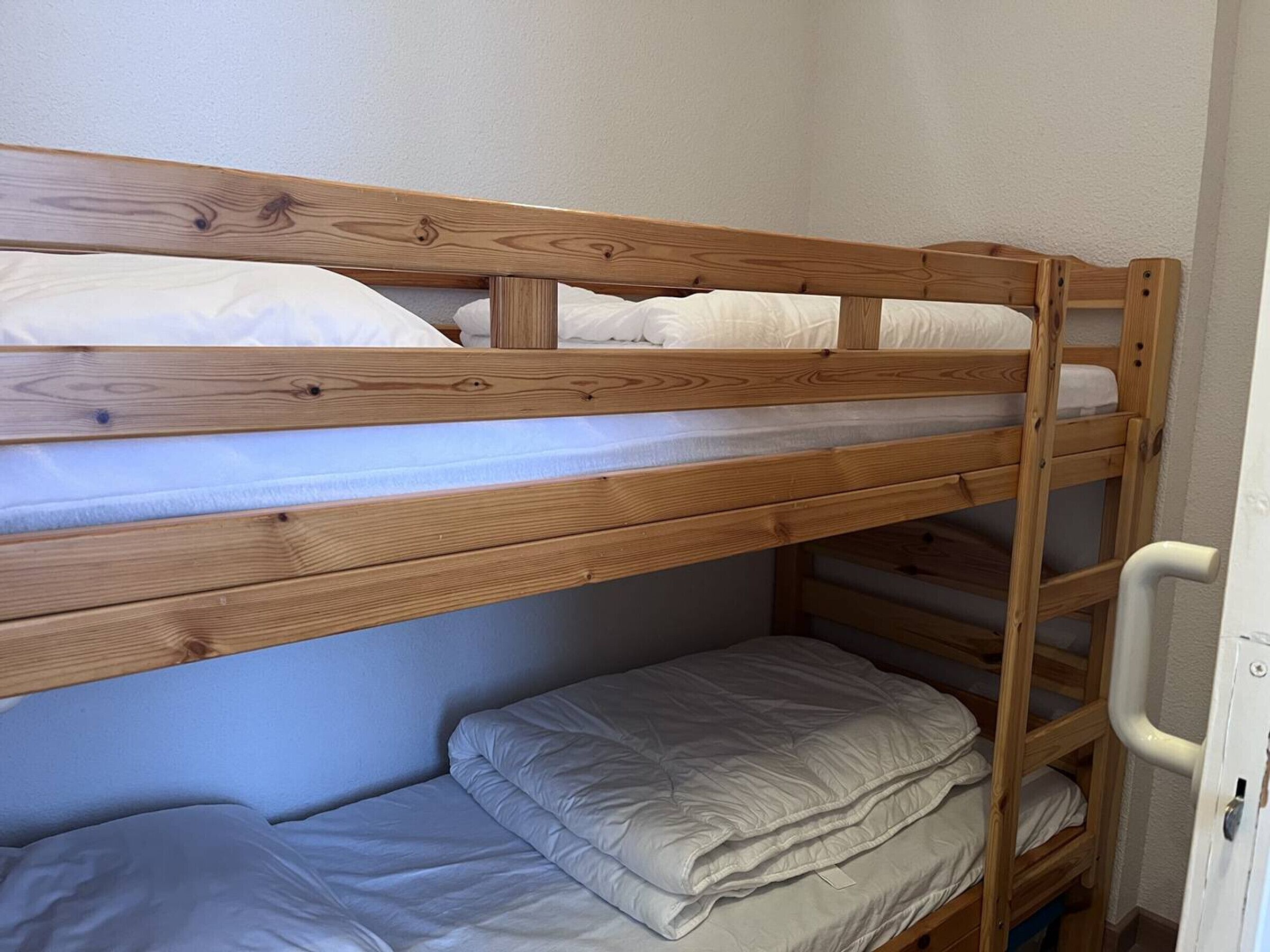 A bunk bed with a wooden frame and a lower bunk with a mattress and pillows.