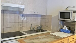 Une cuisine équipée d’une cuisinière, d’un four à micro-ondes, d’un évier et de meubles de rangement en bois.