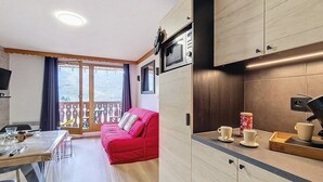A compact kitchen with wooden cabinets, a microwave, and a coffee machine.