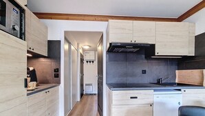 A compact kitchen with wooden cabinets, a built-in oven, and a dishwasher.