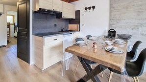 A modern kitchen with wooden cabinets, a built-in stove, and a dining area with a table set for four.
