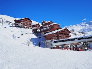 A ski resort with chalet-style buildings, a ski lift, and a snow-covered mountain in the background. - Renovated 2-room Apartment, Southwest Balcony, WIFI, Ski-in/Ski-out (Les Menuires)