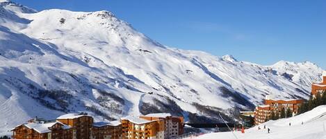 A snow-covered mountain with a ski resort and buildings in the foreground.