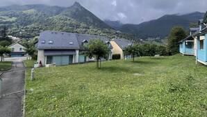 A residential area with houses, a grassy field, and mountains in the background. - Duplex T3 with parking in Cauterets, near cable cars (Cauterets)