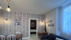 A cozy room with a wooden dining table, white chairs, a blue sofa, and a wooden coffee table. - Bright apartment with 2 bedrooms in Cauterets center (Cauterets)