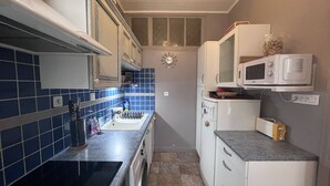 A compact kitchen with a black stove, white cabinets, and a microwave. - Bright apartment with 2 bedrooms in Cauterets center (Cauterets)