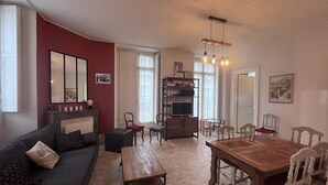 A cozy living room with a sofa, coffee table, and dining table. There is a TV and a bookshelf in the background. - Bright apartment with 2 bedrooms in Cauterets center (Cauterets)