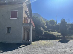 A two-story building with a balcony, a small window, and a gravel driveway. - Spacious House in Cauterets: 4 Bedrooms, Garage, No Pets (Cauterets)