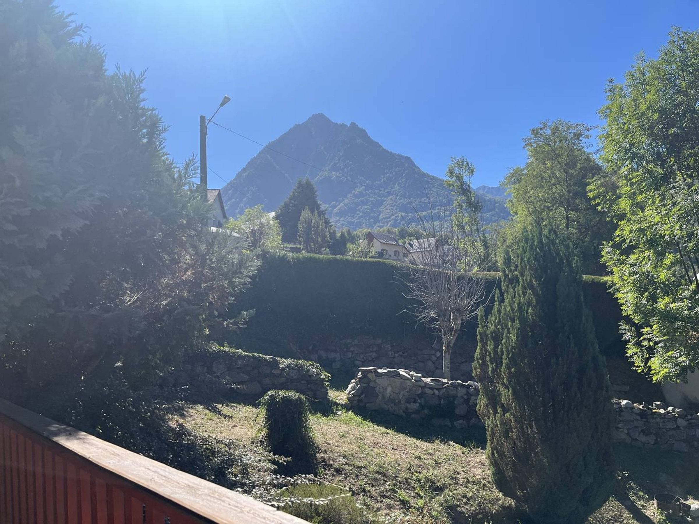 A mountainous landscape with a clear sky, a stone wall, and a wooden fence.
