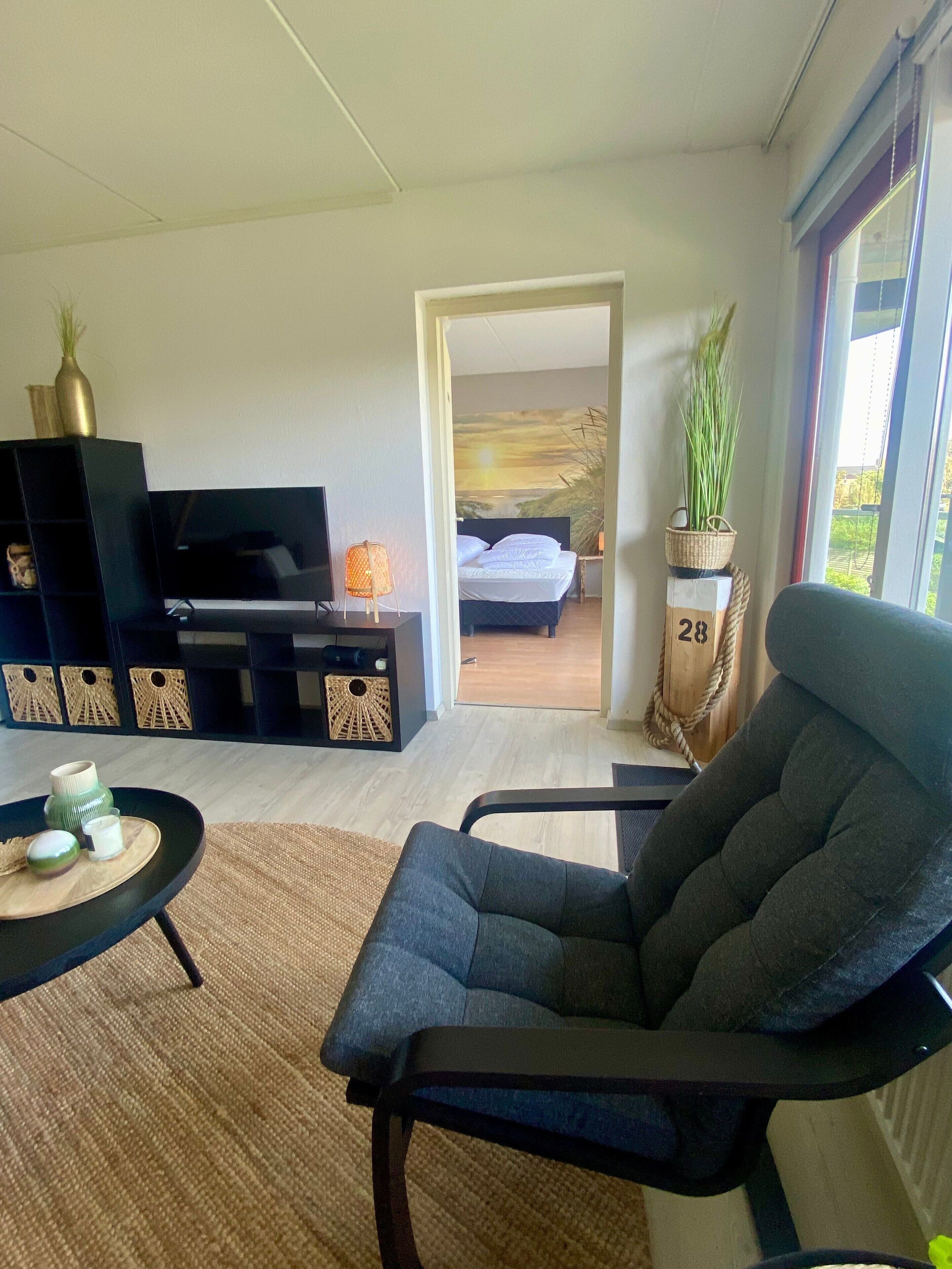 A modern living room with a sofa, a TV, and a small table with decorative items.