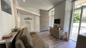 A modern living room with a sofa, a small table, a TV, and a balcony with a railing. - Apartment in Cauterets, near cable cars, 4 ppl, balcony with mountain view (Cauterets)