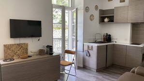 A compact kitchen with a built-in TV, a small dining area, and a balcony with a view. - Apartment in Cauterets, near cable cars, 4 ppl, balcony with mountain view (Cauterets)