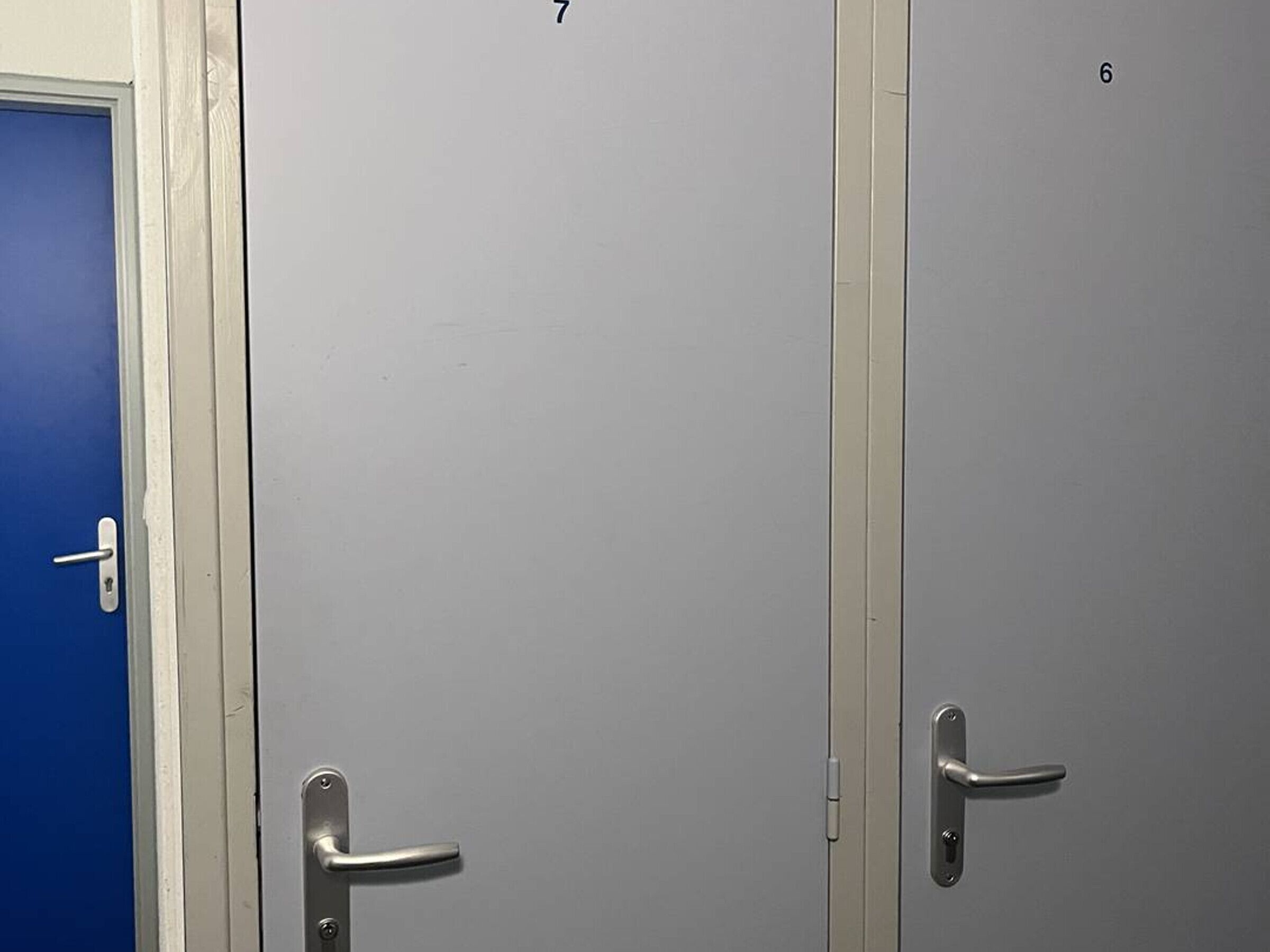 Tres puertas, numeradas 7, 6 y 8, con manijas metálicas y una puerta azul a la izquierda.