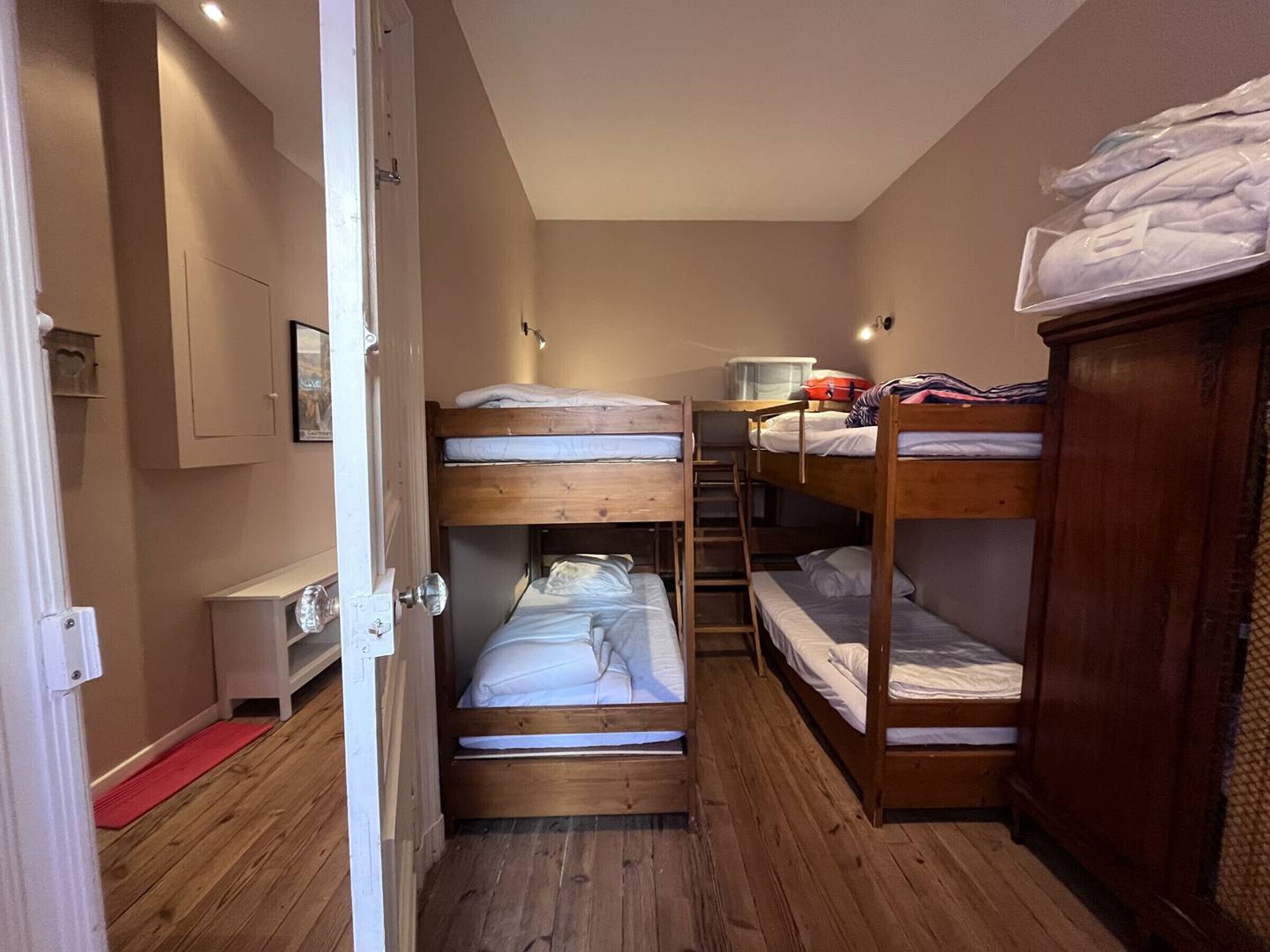 Une chambre de type dortoir, avec des lits superposés, un petit bureau et une armoire.