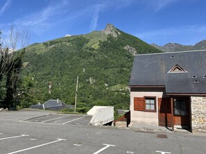 A building with a stone facade, a wooden door, and a parking lot in front.