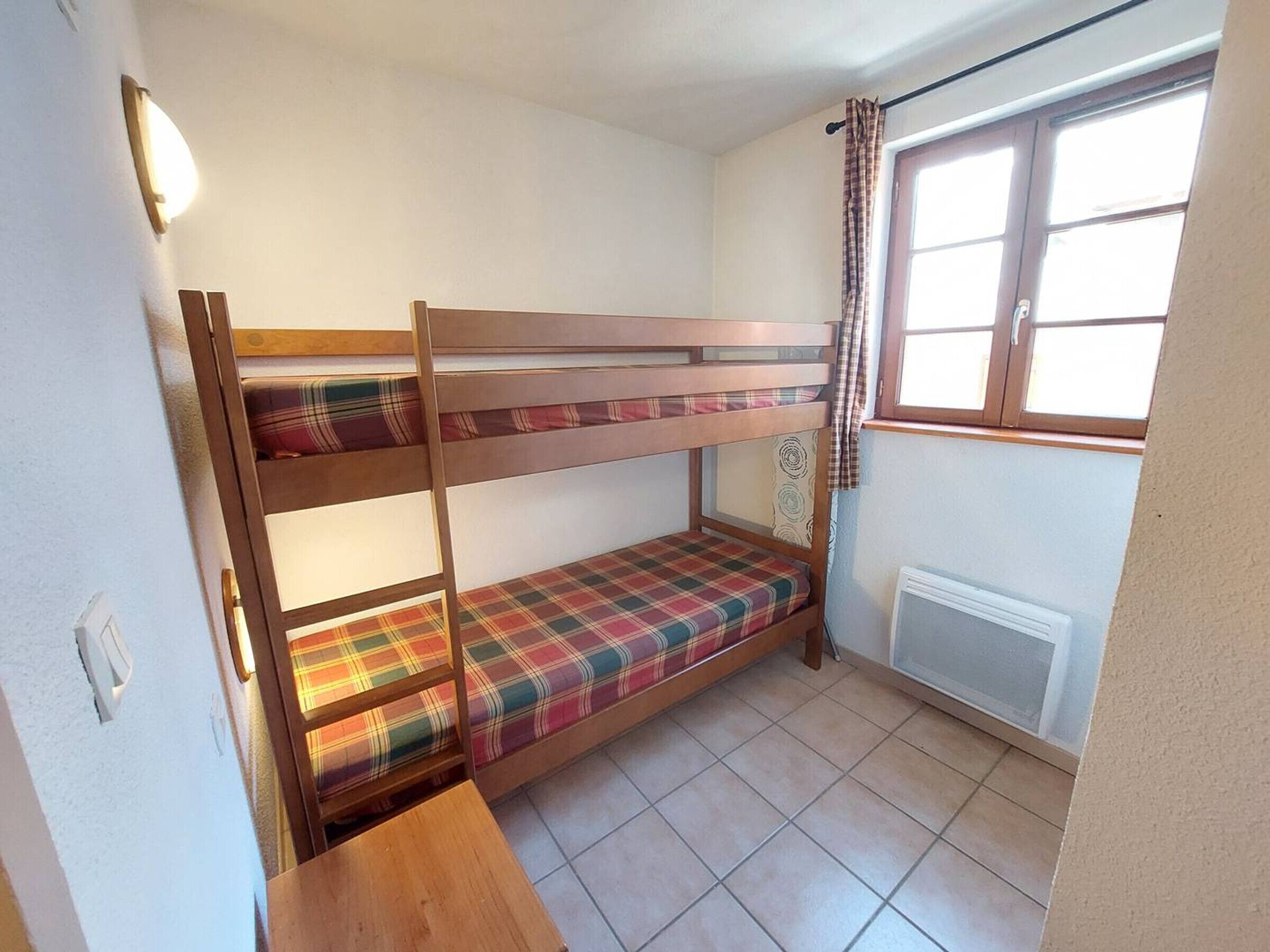 A bunk bed room with a window and a radiator.