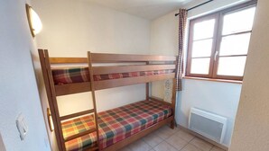 Dormitorio con literas, ventana y radiador.