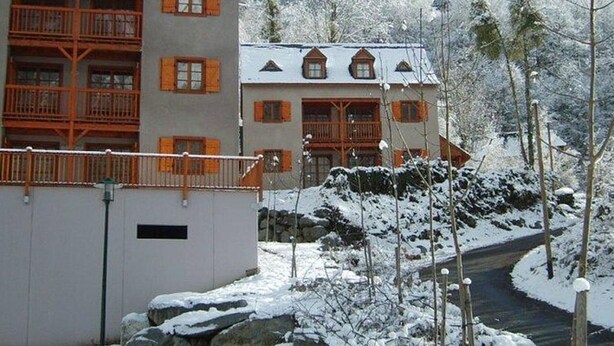 Un edificio de varios pisos con balcones y un paisaje cubierto de nieve.