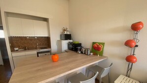 A modern kitchen with a wooden countertop, white chairs, and a microwave.