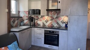A compact kitchen with a microwave, coffee maker, and oven.