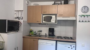 A compact kitchen with wooden cabinets, a microwave, a dishwasher, and a coffee maker.