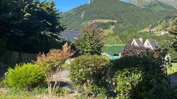 A rural landscape with a mountain in the background, a road, and a few houses.
