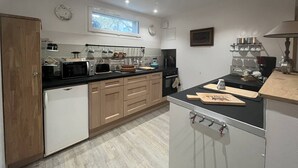 A modern kitchen with wooden cabinets, a black countertop, and a built-in oven. There is a window above the sink, and various kitchen utensils are visible.
