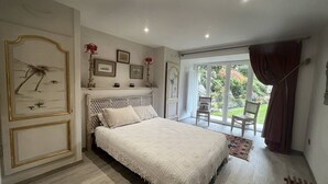 A bedroom with a bed, a large window, and a view of a garden.