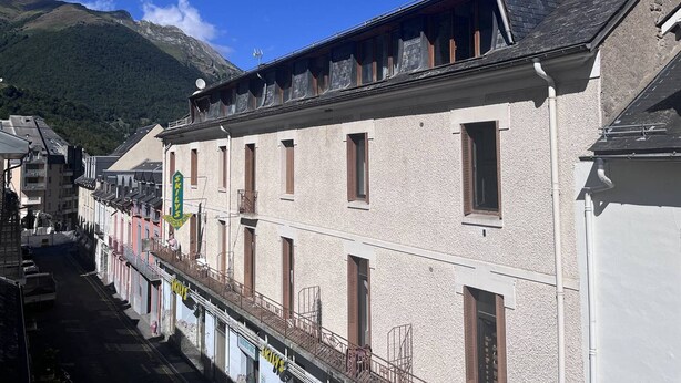 A building with a balcony, a sign reading "SKILVEC," and a mountain in the background. - Family apartment in Cauterets with balcony, ski locker, perfect for 4 guests (Cauterets)