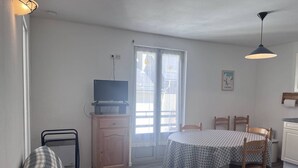 A room with a bed, a TV on a wooden cabinet, a dining table with chairs, and a window with a view of the outside. - Family apartment in Cauterets with balcony, ski locker, perfect for 4 guests (Cauterets)