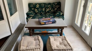 A corner room with a green sofa, a wooden table, and two beige poufs.