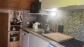 A compact kitchen with wooden cabinets, a built-in oven, a coffee maker, and a kettle.