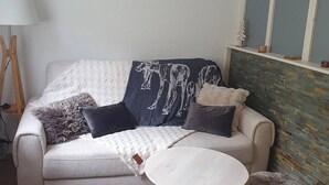 A living room with a sofa, a round coffee table, and a lamp. - Charming chalet for 4 in Cauterets with parking (Cauterets)