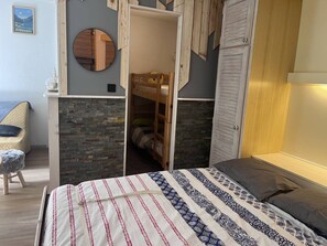 Ein Schlafzimmer mit einem Etagenbett, einem runden Spiegel, einem Holzschrank und einer Wand mit Steinmuster.
