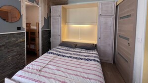 A bedroom with a bed, a wardrobe, a mirror, and a built-in bench. - Charming chalet for 4 in Cauterets with parking (Cauterets)
